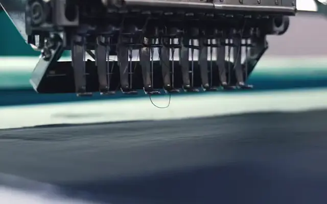 Multi-head embroidery machine stitching over dark garment fabric in SenLin’s workshop