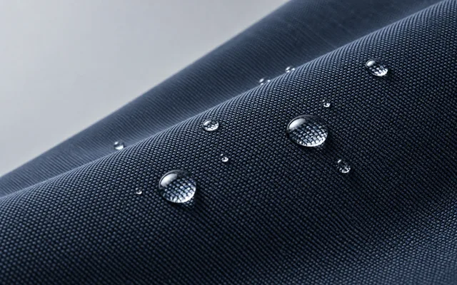Clear water droplets on folded dark blue woven fabric