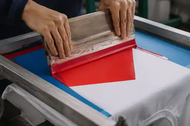 Screen-printing squeegee applying a simple ink shape to cotton fabric