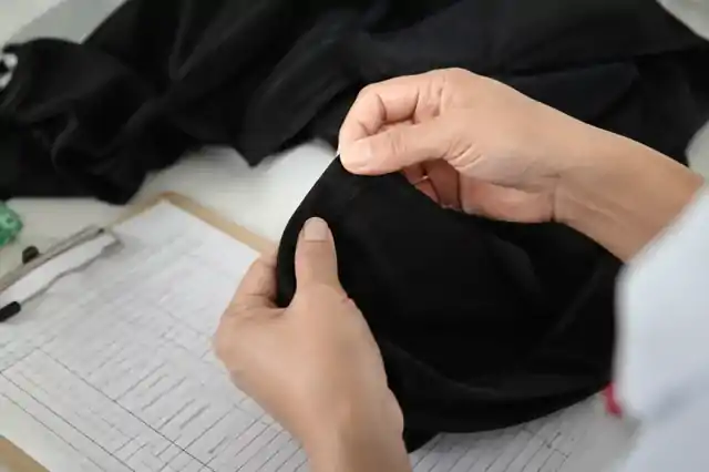 Garment seam inspection beside a measurement record and clipboard