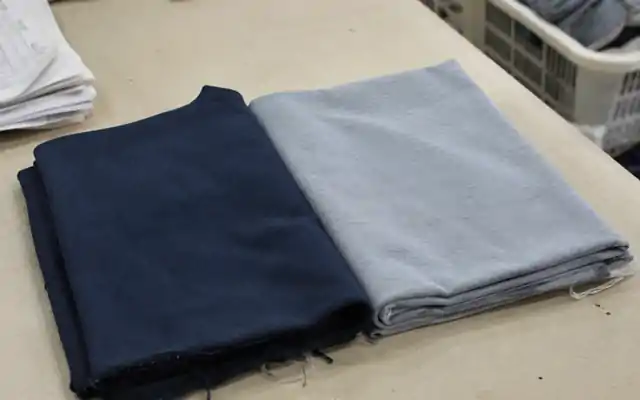 Matte navy and smooth grey knitted fabric samples on a sample-room table