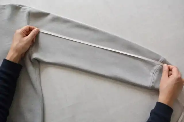 Sleeve of a laid-flat sweatshirt checked with a measuring tape