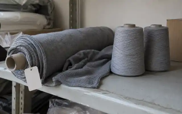 Yarn cones and knitted fabric roll on a stockroom shelf