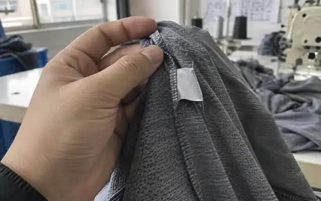 Care label inside the side seam of a grey sports tee
